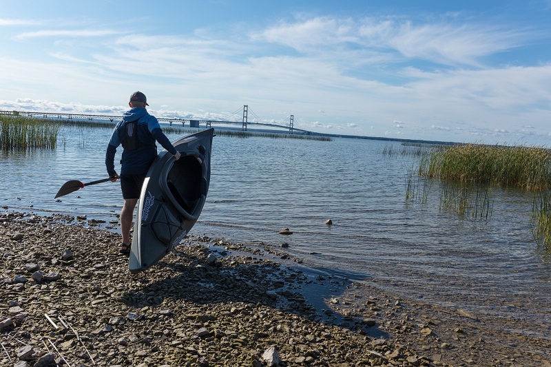 Man at water's edge ready to launch a kayak